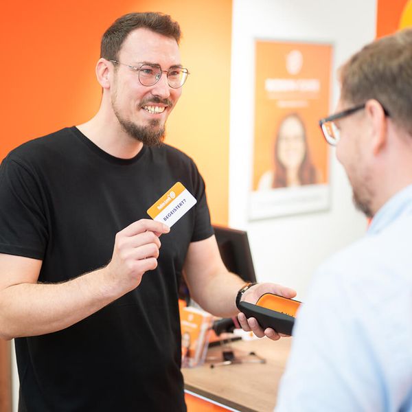 Optiker bei Robin Look übergibt Brille an Kunden